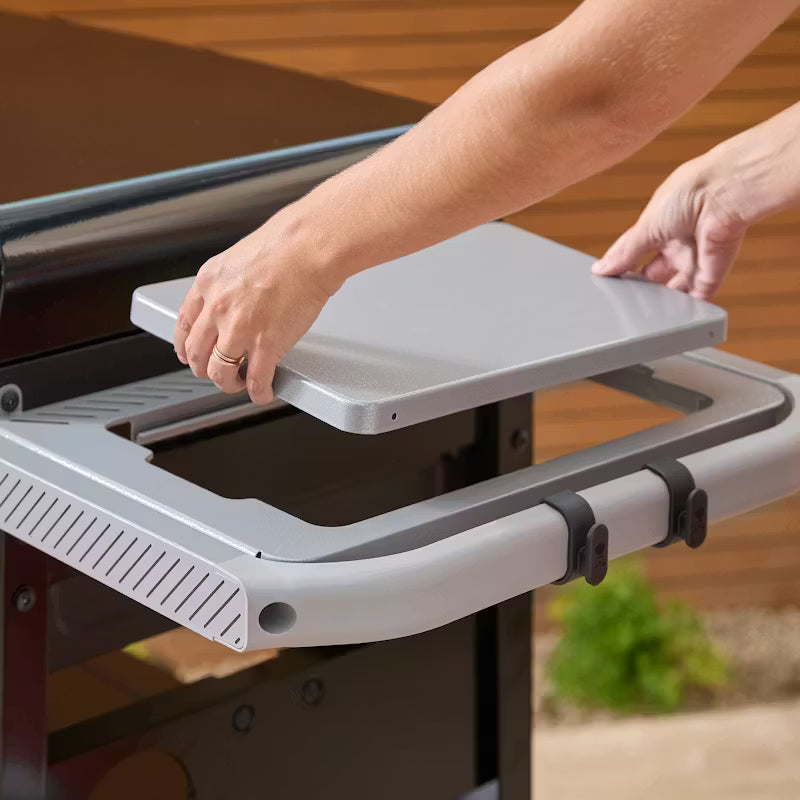 Hands placing the Weber Slate GP 71cm Premium Griddle cover on the side table frame of a grill.