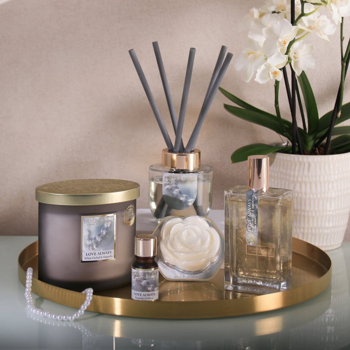 Fragrance Wax Melt Love Always shaped like a white rose on a gold tray with matching scented products and orchid plant.