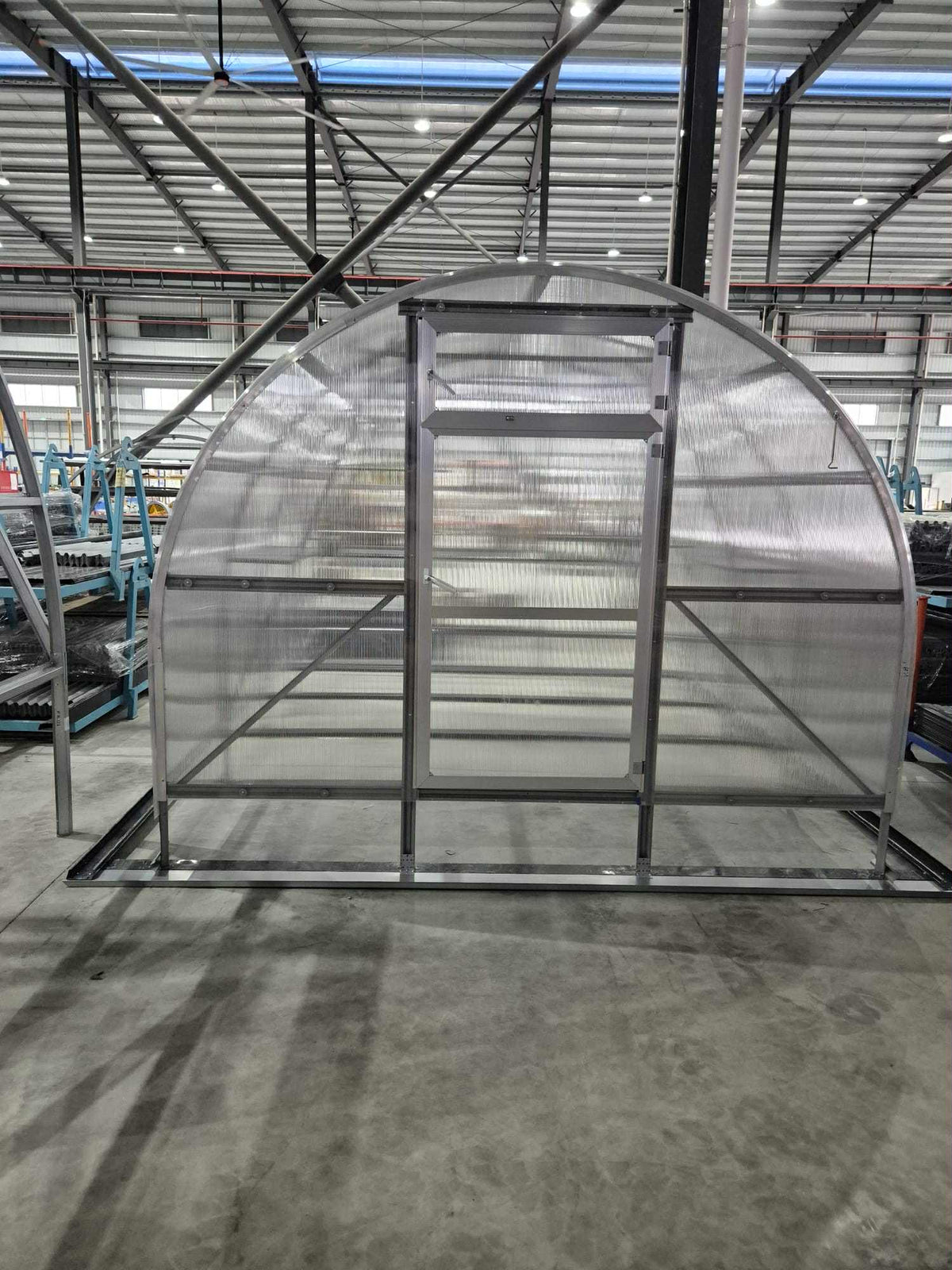 Front view of Sigma Lux 3m x 6m greenhouse frame with clear 6mm polycarbonate panels indoors