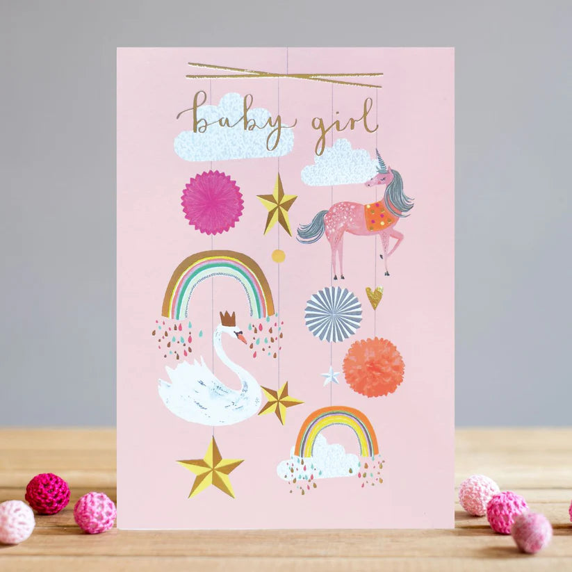 Pink baby girl card with hanging mobile illustrations of swan, unicorn, rainbows, stars, and clouds