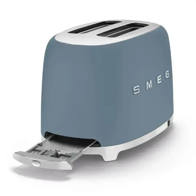 Smeg 2 slice toaster in storm blue with crumb tray extended, angled view showing slots and logo.