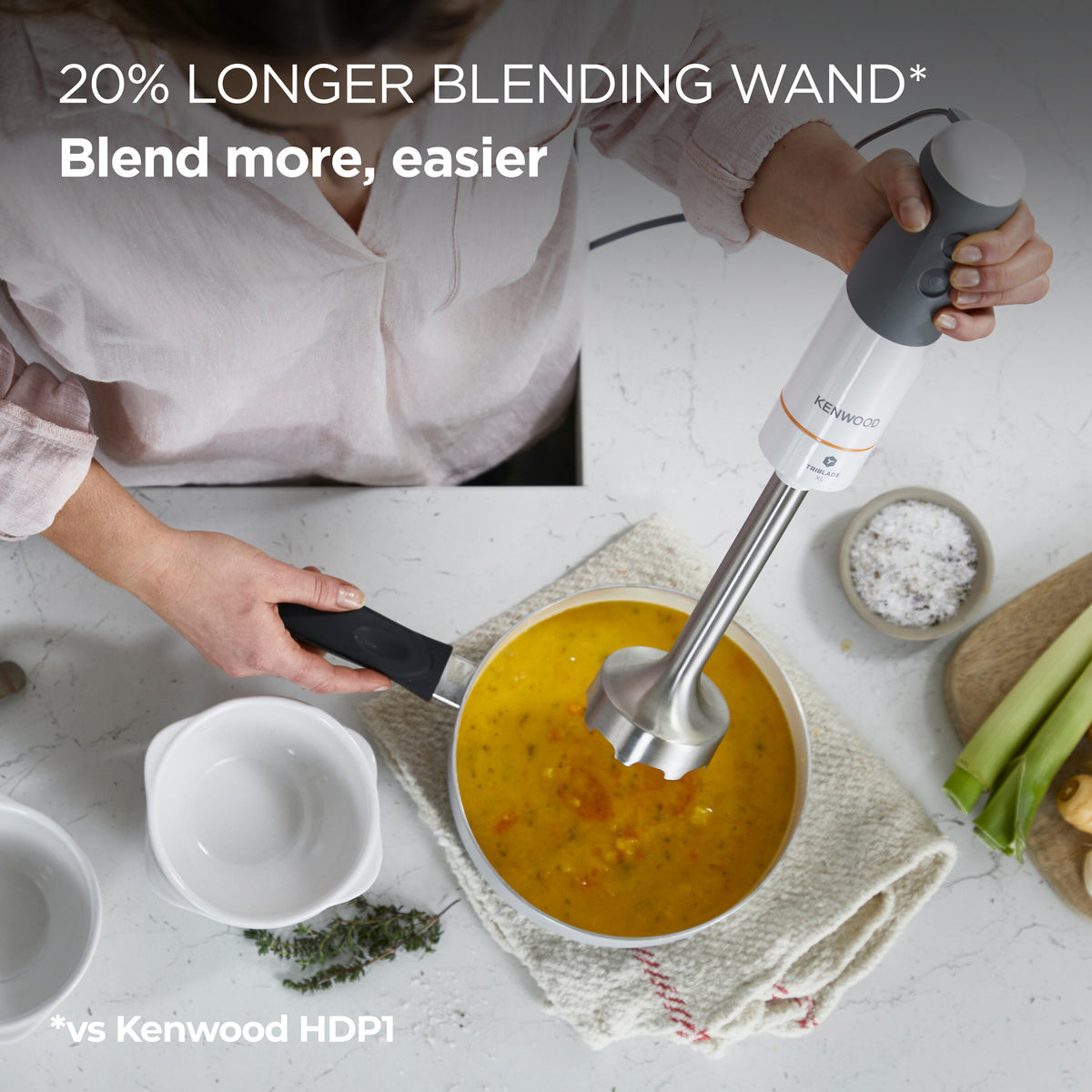 Person using Kenwood Triblade 850W hand blender to blend soup in a pot on a kitchen counter