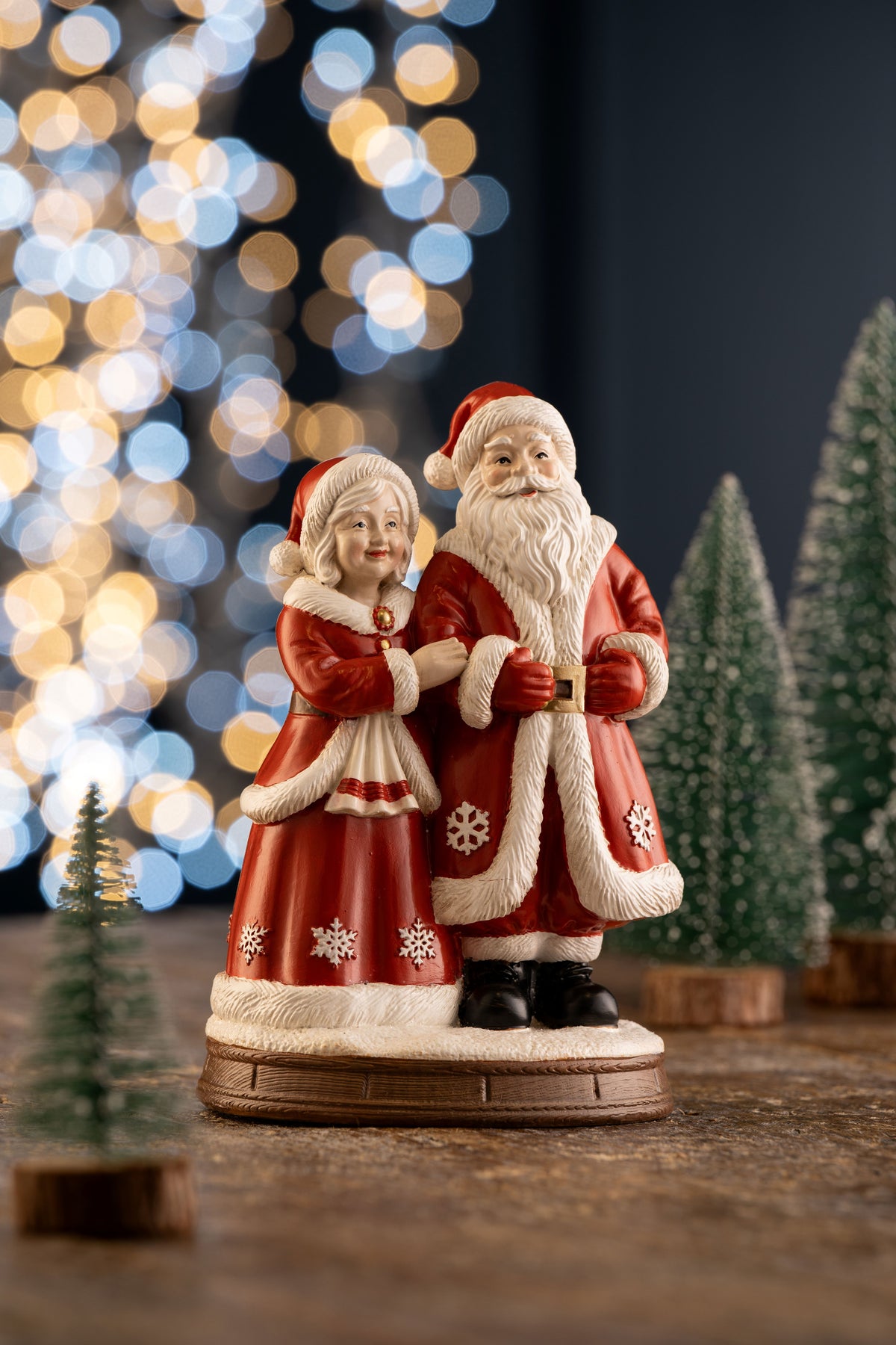 Aynsley Mr & Mrs Claus figurine with Santa and Mrs. Claus in red coats, standing on a wooden base.