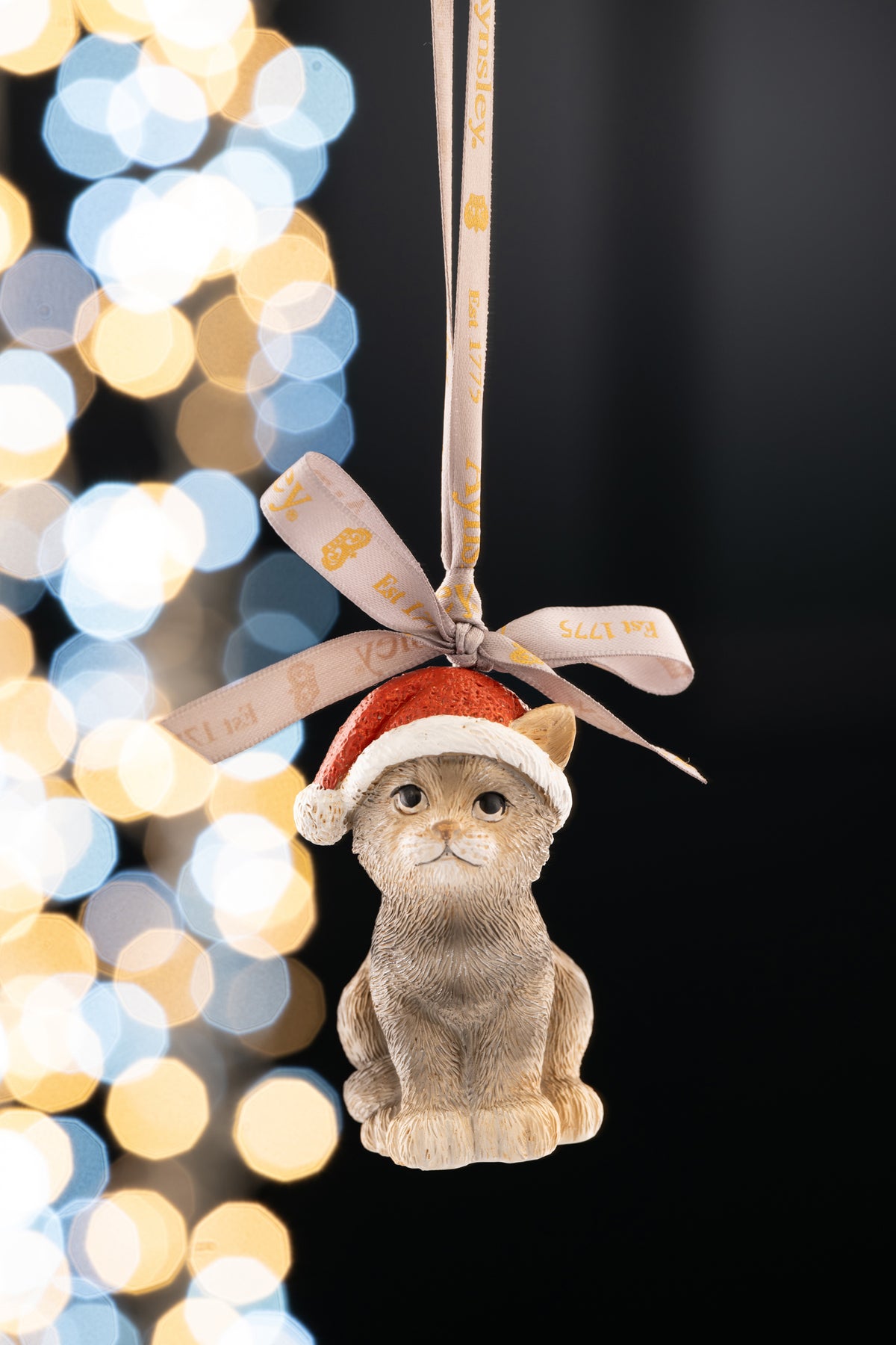 Aynsley Christmas Kitten ornament wearing a red Santa hat, hanging by a ribbon with gold text.