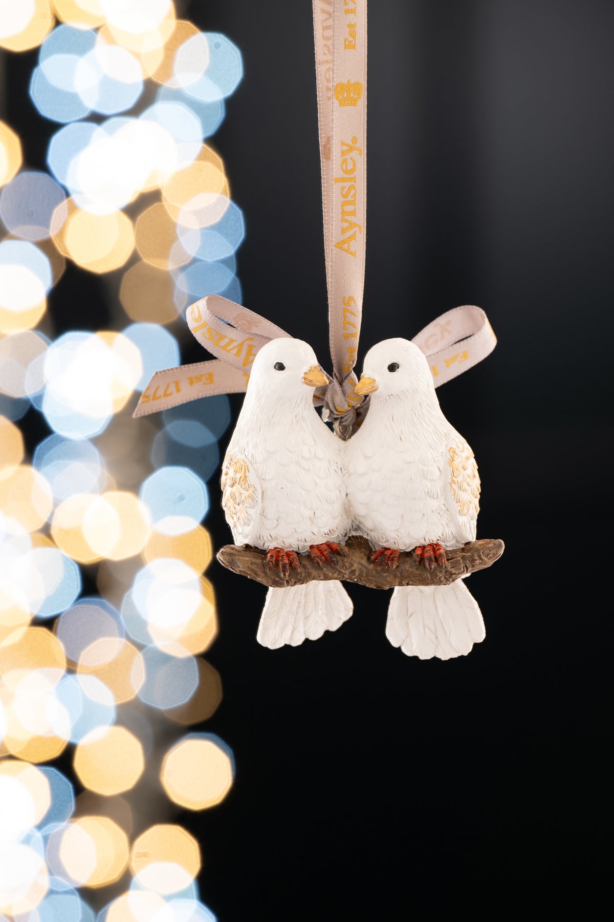 Two white turtle doves with gold accents perched on a branch, hanging from an Aynsley ribbon.