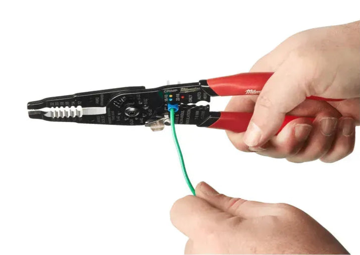 Milwaukee Multi-Purpose Wire Stripper with Crimper stripping green insulated wire, held in two hands against white