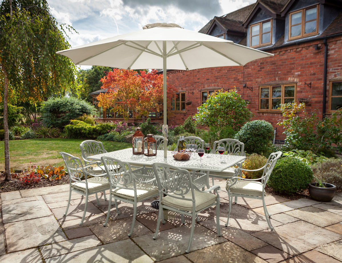Amalfi 8 seat rectangular garden dining set in maize with wheatgrass cushions and white parasol on patio.
