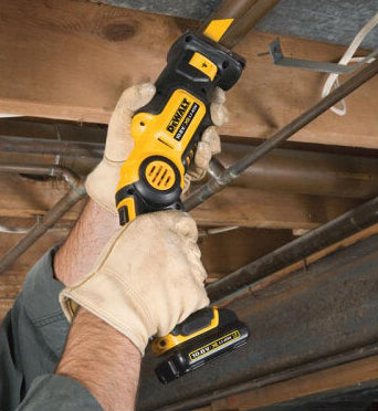 Person wearing gloves using a DeWalt reciprocating saw with a metal cutting blade on a wooden beam.