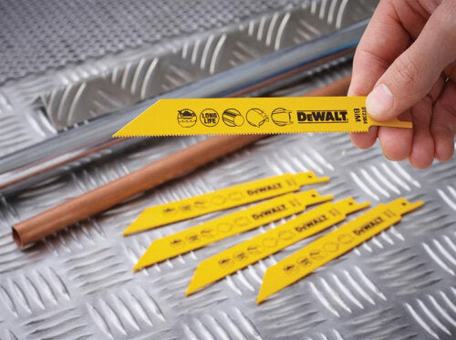 Hand holding a yellow DeWalt bi-metal reciprocating blade with four more blades on a metal surface next to copper pipes.