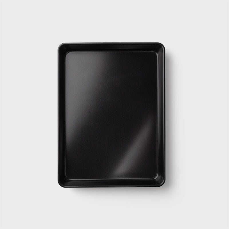 Black carbon steel extra large deep oven tray shown from above on a light background