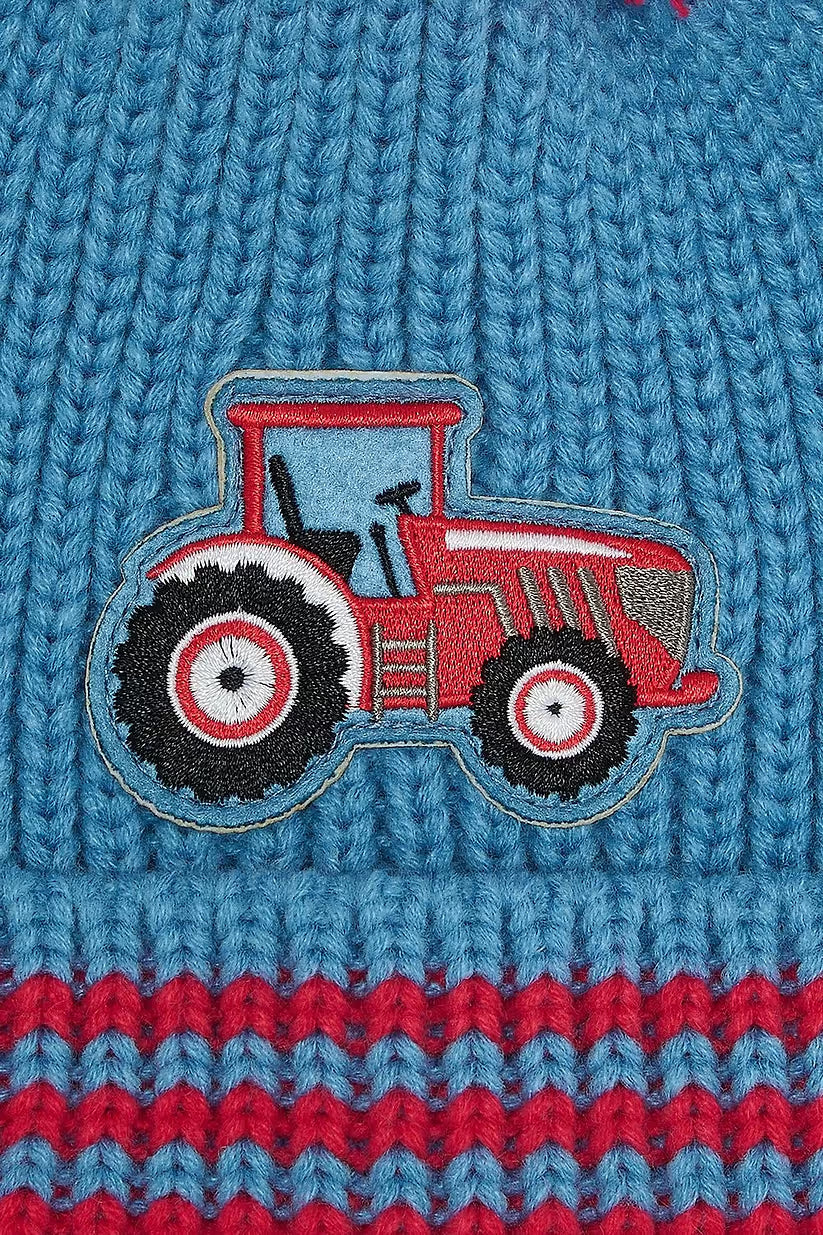 Close-up of blue knit Bobbie Hat with red tractor patch and red striped detail at the bottom edge.