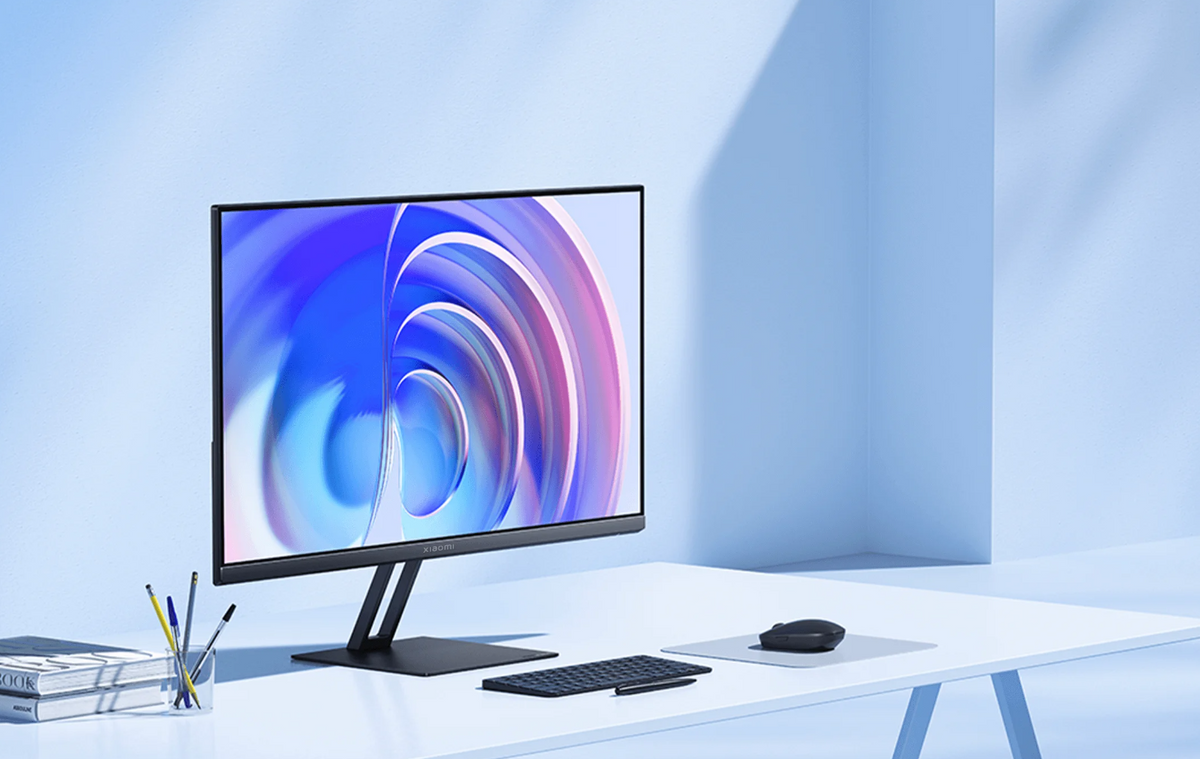 Xiaomi A24i 24" FHD monitor on a white desk with keyboard, mouse, and pens in a bright room