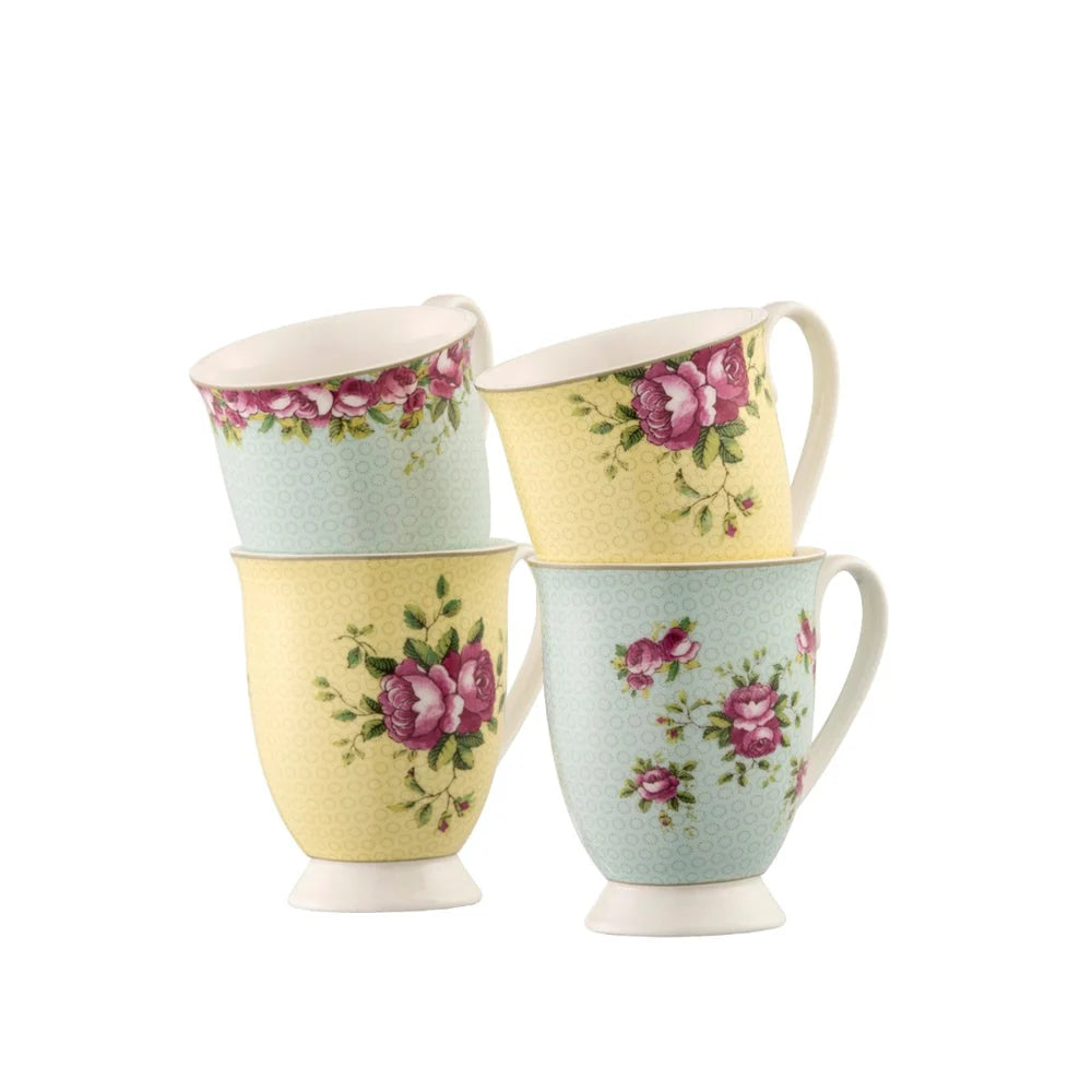 Set of four Archive Rose footed mugs in pastel yellow and mint with pink floral patterns on white background.
