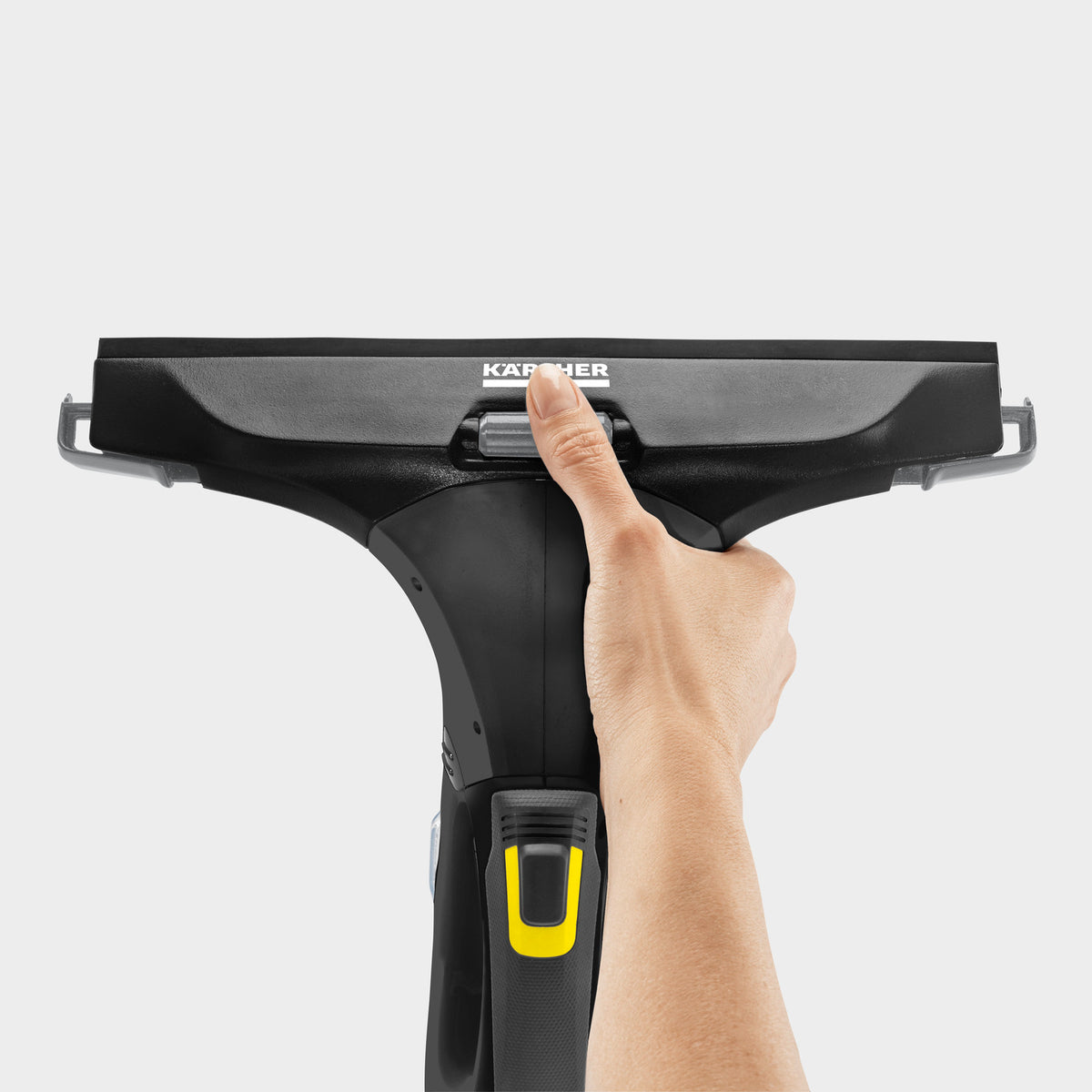Hand holding the top of a black Karcher WV5 Anniversary Window Vac with yellow button on handle against white background