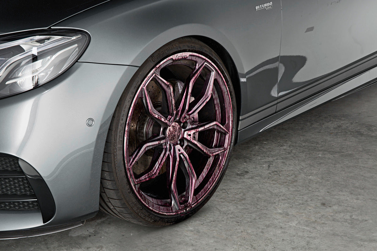 Close-up of a car wheel with Karcher Rim Cleaner applied, showing purple cleaning foam on the rim.