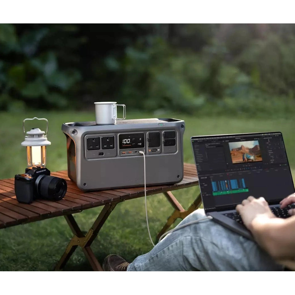 DJI Power 1000 portable power station on a wooden table powering a laptop outdoors at dusk