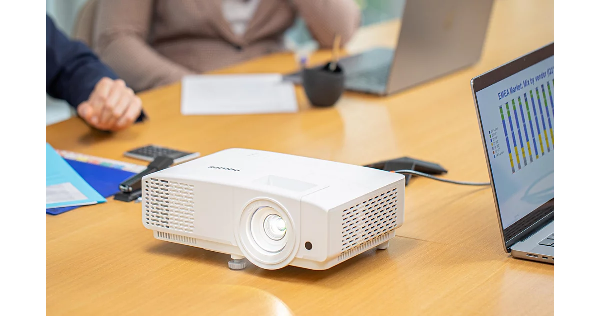 Philips Propix 850 projector on a conference table projecting light, with laptop and documents nearby.