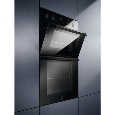 Built-in Electrolux black double oven with upper door open, integrated into blue cabinetry.