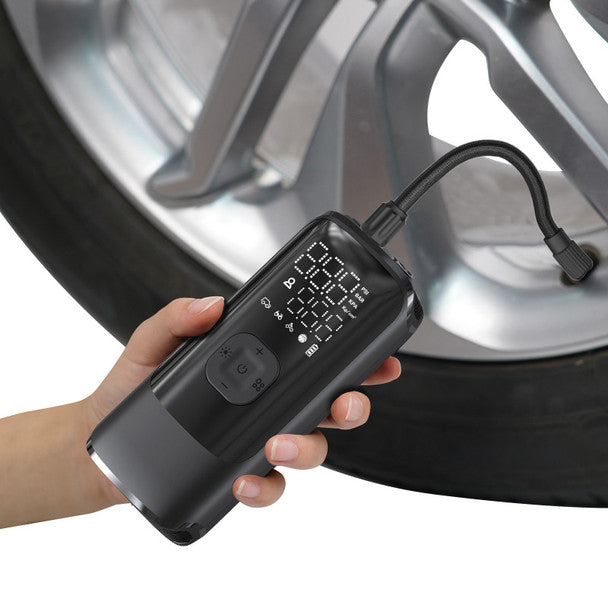 Hand holding Energizer Portable Air Compressor inflating a car tire, digital display visible on device.