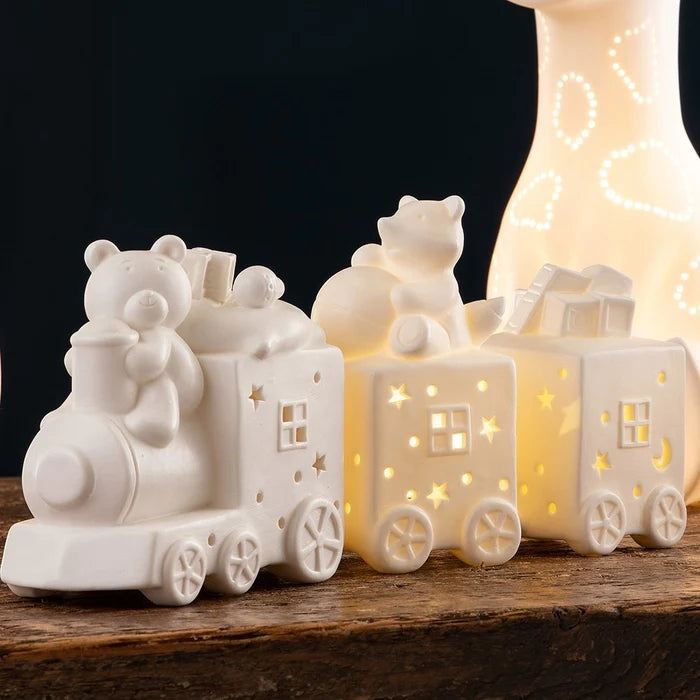 White ceramic Luminaire Choo Choo Train LED with bear figures and star-shaped light cutouts on wooden surface