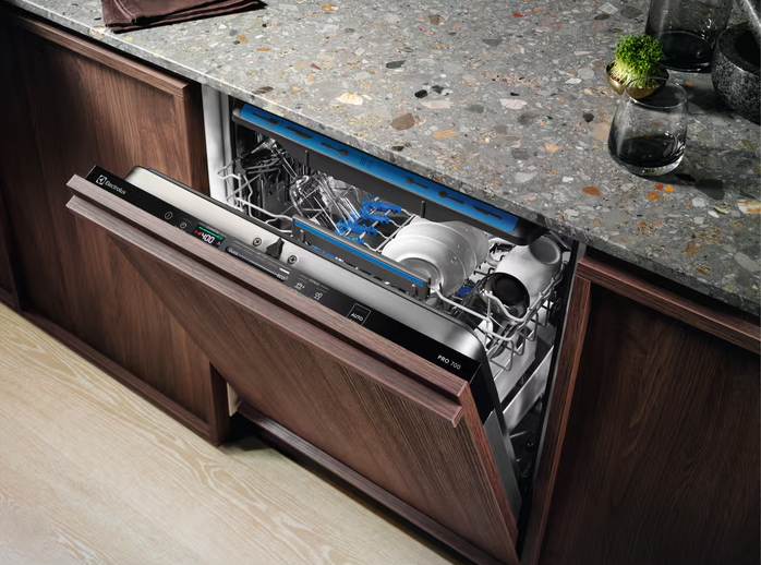 Electrolux Integrated 3 Drawer Dishwasher open with dishes inside, built into dark wood kitchen cabinetry.