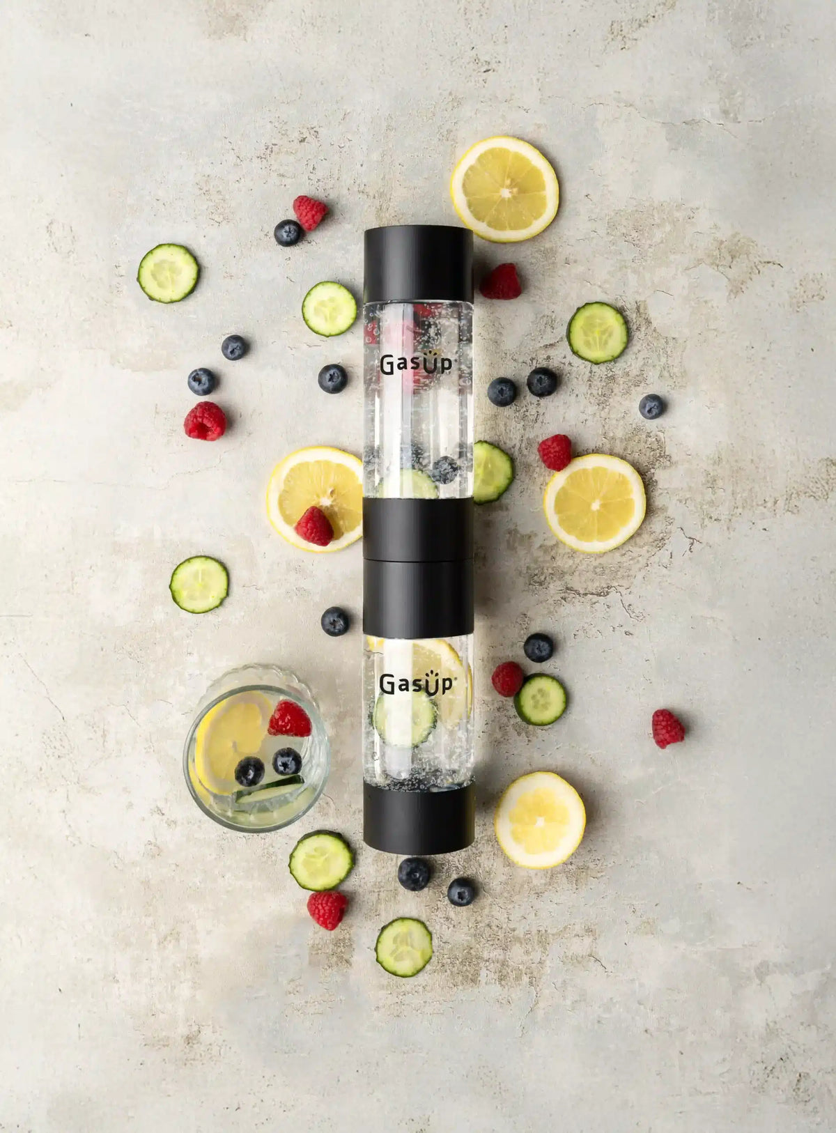 GasUp 2 black bottles with infused water surrounded by lemon, cucumber, raspberry, and blueberry slices.