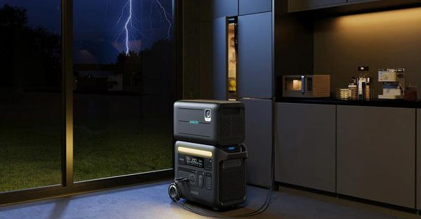 Anker BP2600 Portable Power Expansion Battery connected and charging indoors near a window at night.