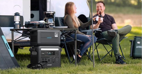 Anker BP2600 Portable Power Expansion Battery stacked on a power station under a camping table outdoors.