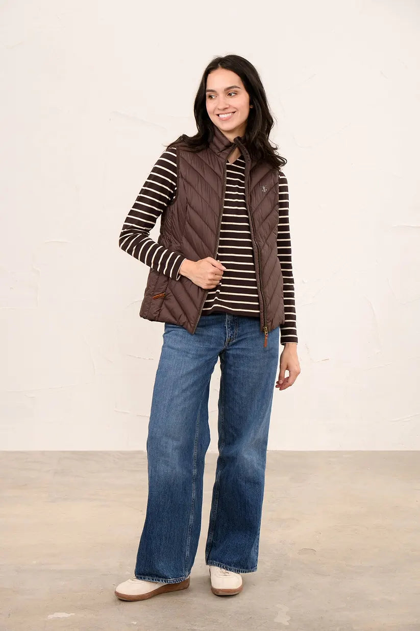 Woman wearing a cocoa-colored quilted Laurel Ladies Gilet over a striped long-sleeve top and blue jeans.