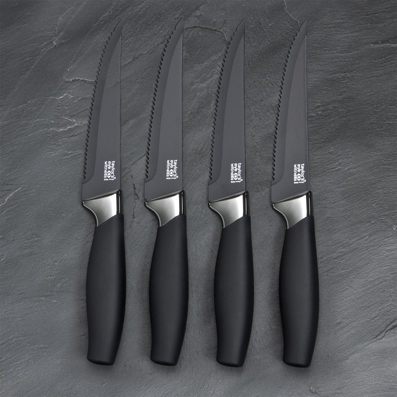 Four Brooklyn 4 Piece Steak Knives with serrated black blades and chrome accents on a dark slate surface.