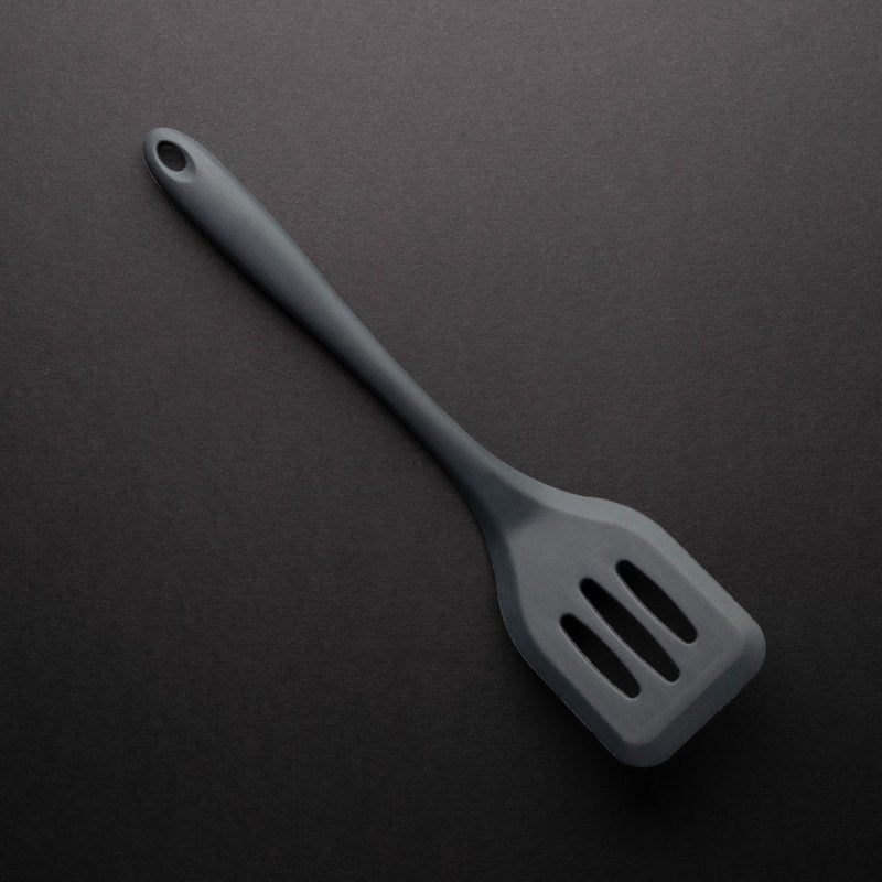 Graphite-colored 28cm slotted turner with a long handle and three slots on a dark background