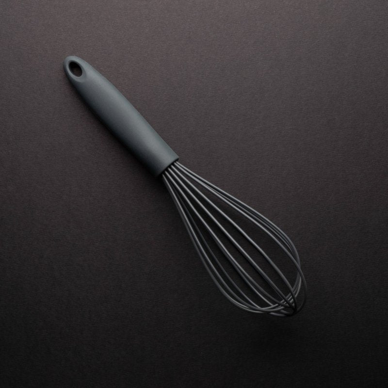 Graphite 25cm silicone whisk with ergonomic handle on dark background