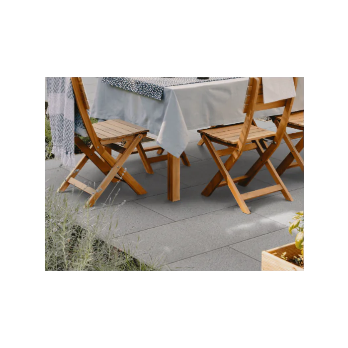 Outdoor patio with Kilsaran Massimo Flag Silver Granite paving under a table and wooden chairs