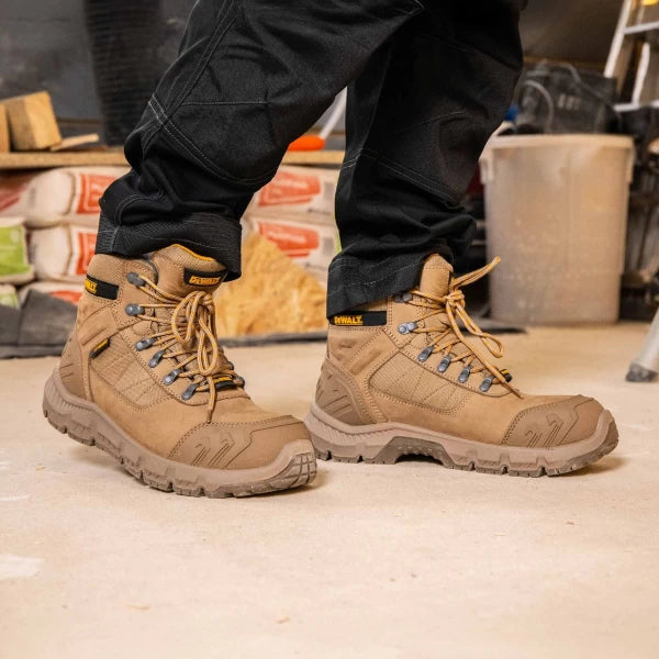 DeWalt Milburn Stone Waterproof Boots worn with black pants on a construction site floor.