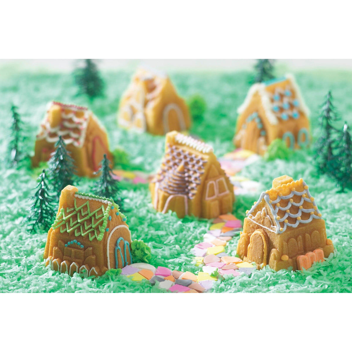 Mini gingerbread houses decorated with icing and candy on green shredded coconut grass