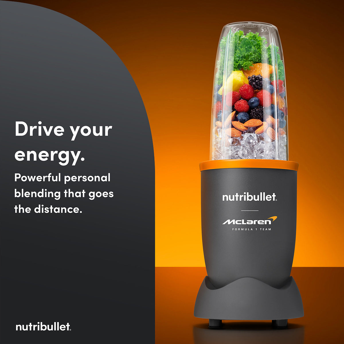 Nutribullet 900 McLaren blender with fruits, nuts, and ice in clear blending cup on orange background.