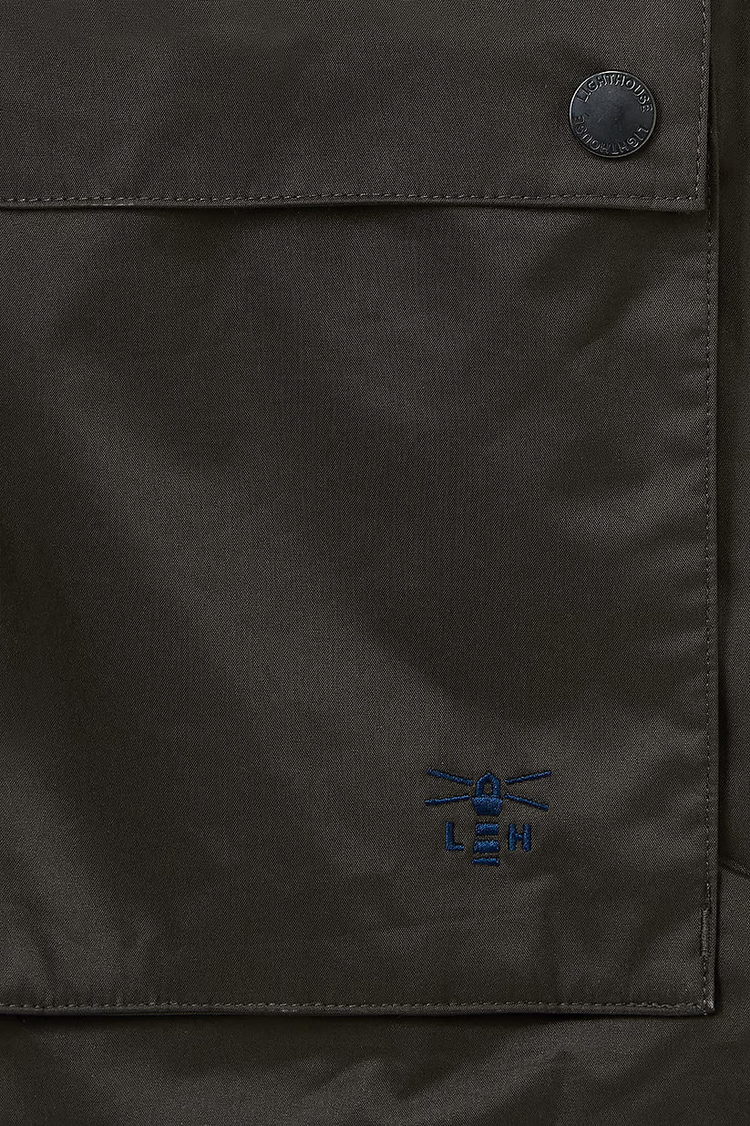 Close-up of chocolate Oxford coat pocket with blue lighthouse logo embroidery and black button detail