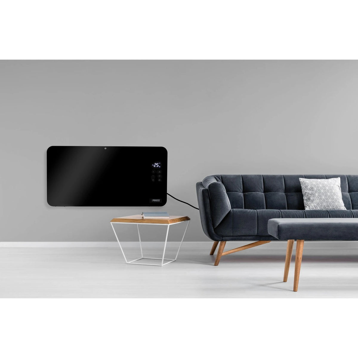 Black Princess Smart Panel Heater 1500W mounted on gray wall beside dark gray sofa and wooden table