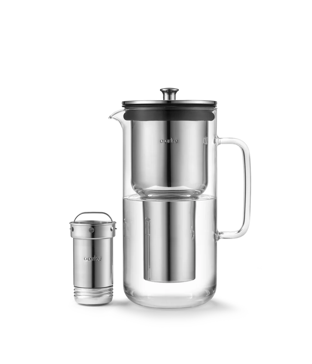 Aarke Purifier glass water filter pitcher with stainless steel filter cartridge beside it on white background