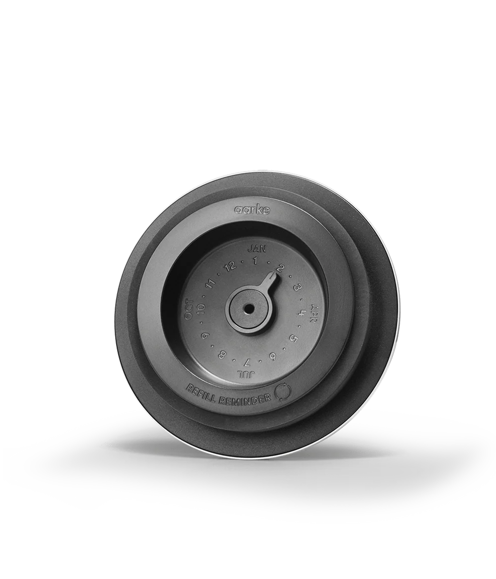 Top view of Aarke Purifier glass water filter pitcher lid with refill reminder dial and month markings.