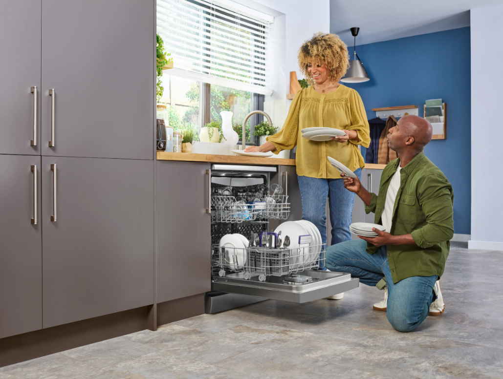Beko 16 Place Stainless Steel Dishwasher open in kitchen with couple loading dishes inside.