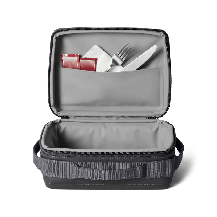 Open Yeti Eu Daytrip insulated lunch box in charcoal with utensils and condiment packets in lid pocket.