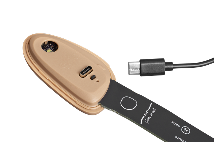 Smart Pebble plant care device by Elho with USB-C charging port and sensor strip for soil placement.