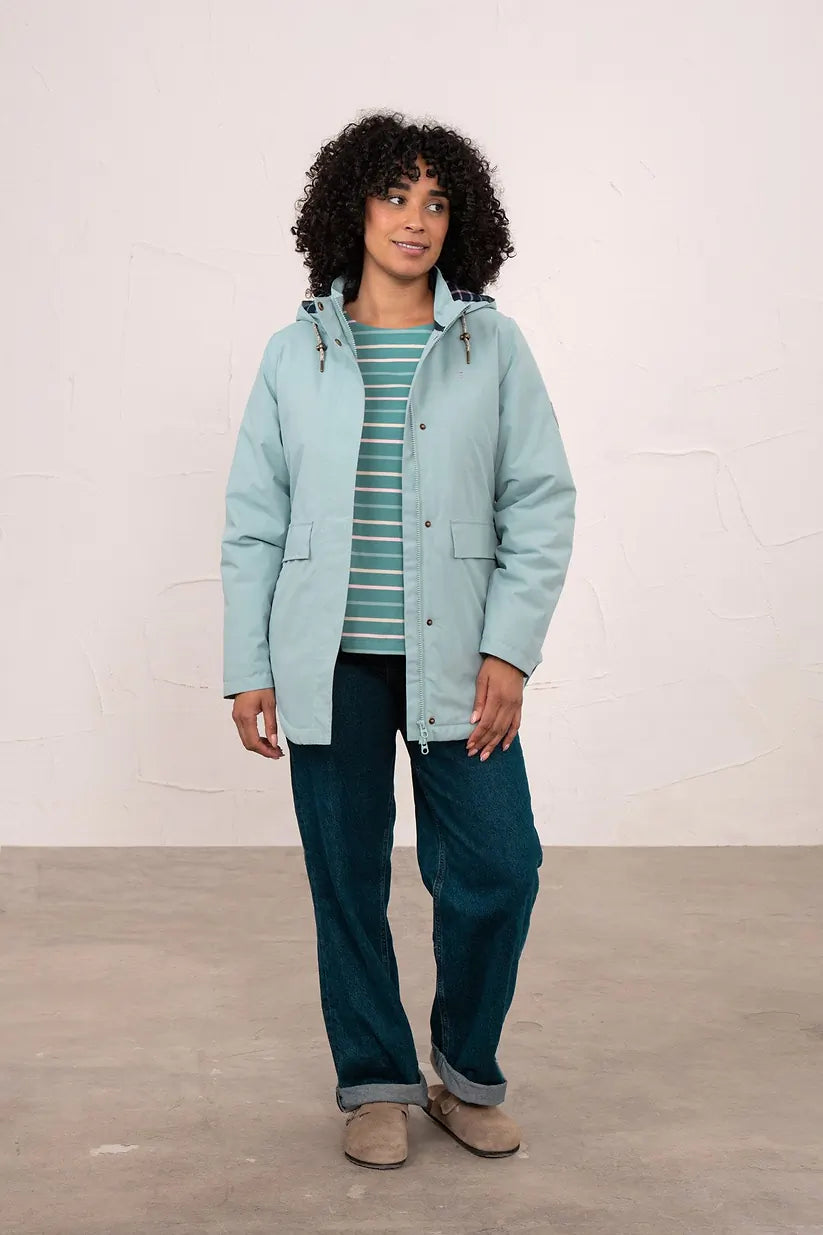 Woman wearing a duck egg blue Tess Ladies Waterproof Coat with hood, paired with striped top and jeans.