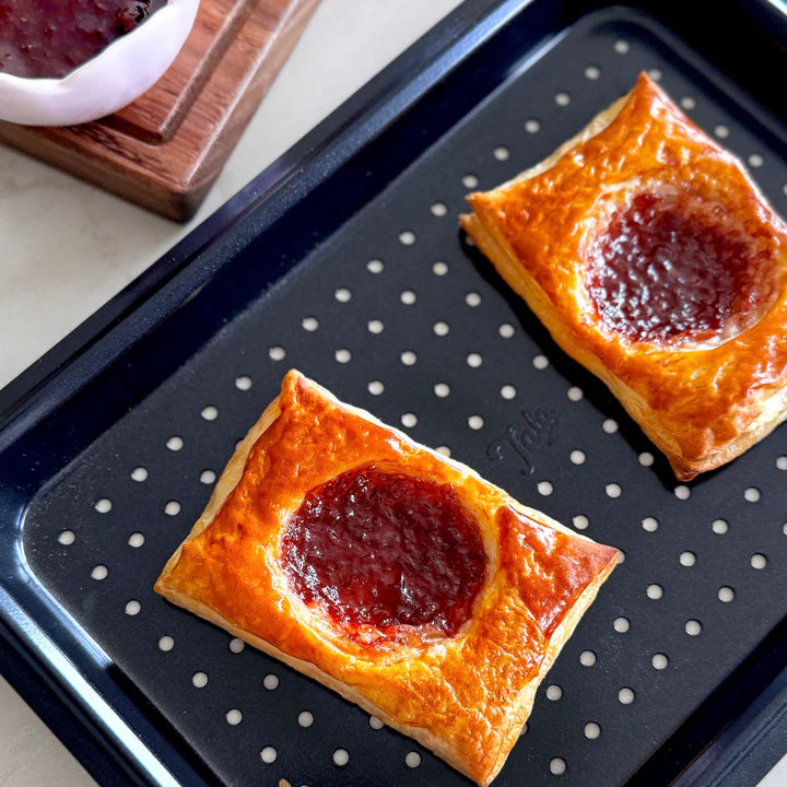 Tala Eclipse Crisper Tray with two baked jam-filled pastries on a perforated black baking tray.