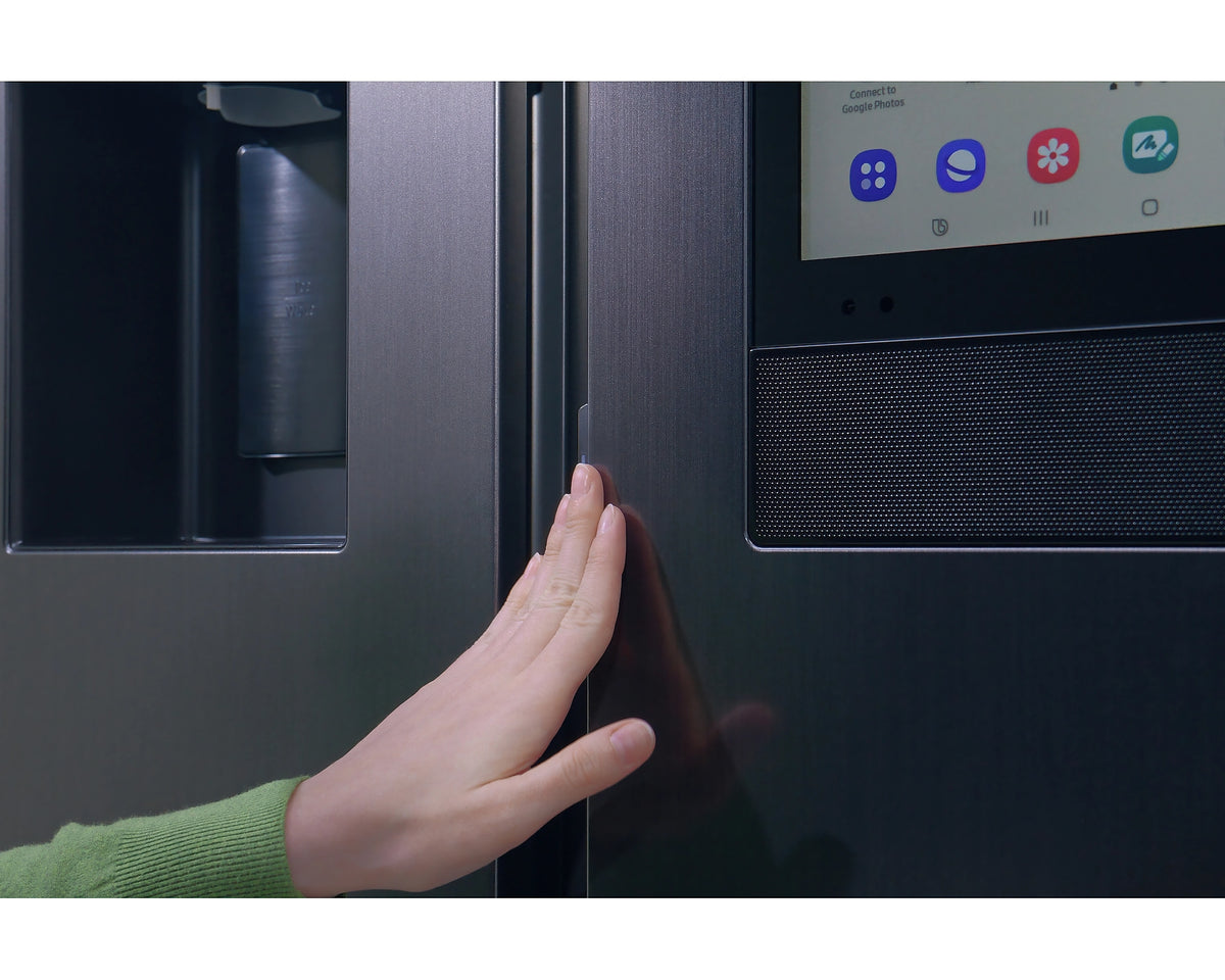 Close-up of a hand opening the silver Samsung Smart SBS Family Hub fridge door showing part of the touchscreen panel.