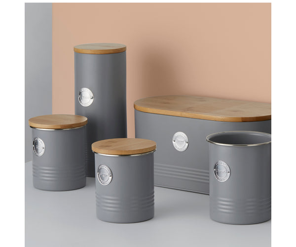 Set of five living grey pasta jars with wooden lids and metal labels on a neutral background