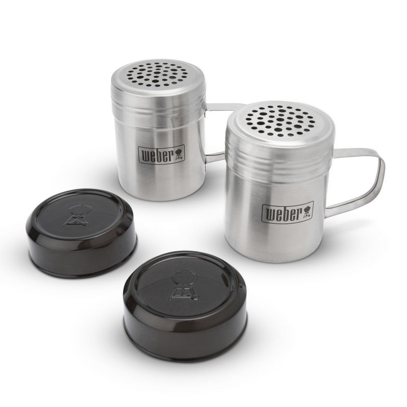 Two stainless steel Weber shakers with handles and two black plastic lids for smashed burger griddle kit